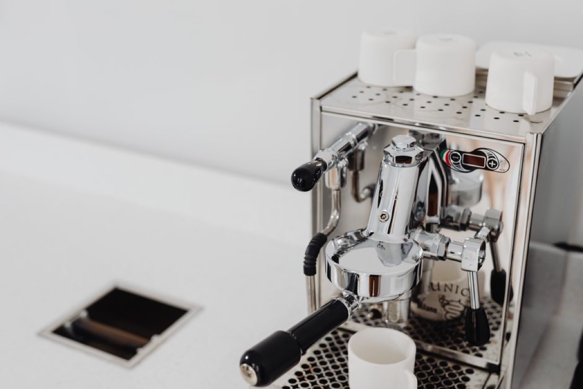 Stainless steel espresso machine with cups on warming tray