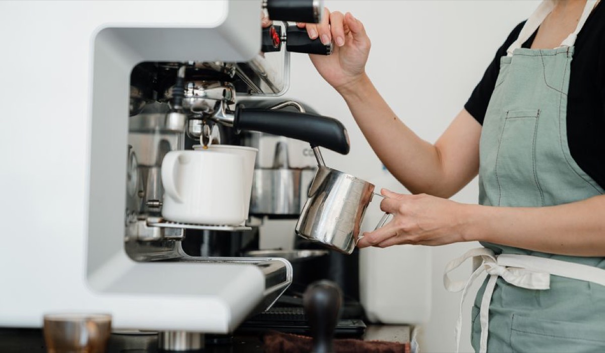 Barista steaming milk with professional steam wand for espresso drinks