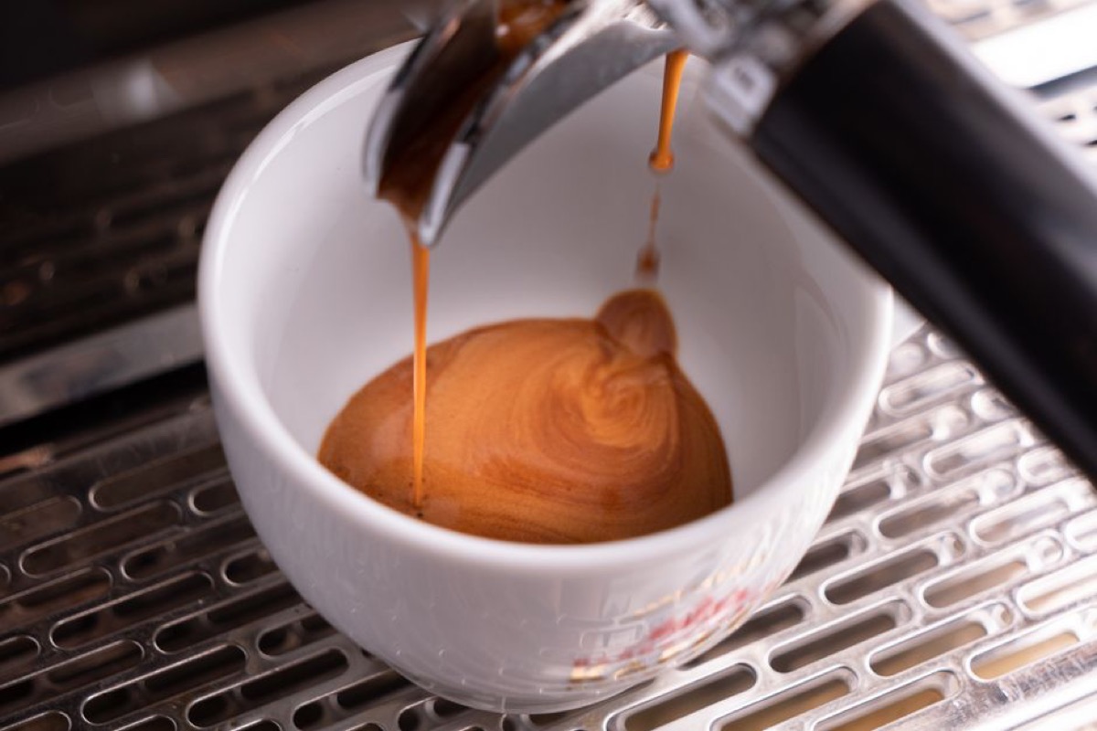 Espresso shot extracting through a bottomless portafilter showing crema quality