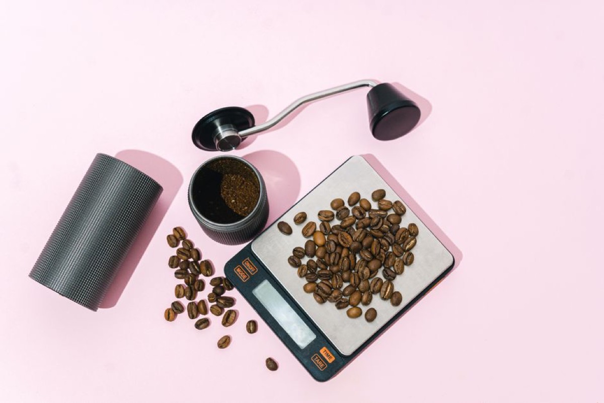 Coffee beans weighed on a digital scale next to a grinder for single-dose workflow