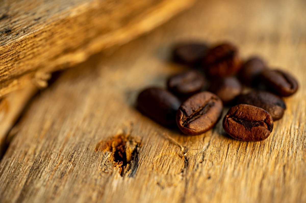 Fresh roasted coffee beans scattered on rustic wooden surface