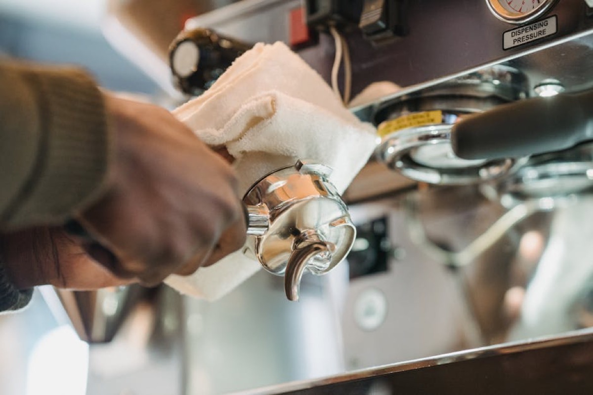 Barista cleaning espresso machine portafilter for maintenance