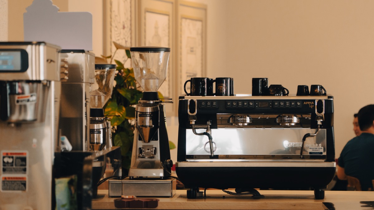 Professional espresso grinder and machine on bar counter with warm lighting