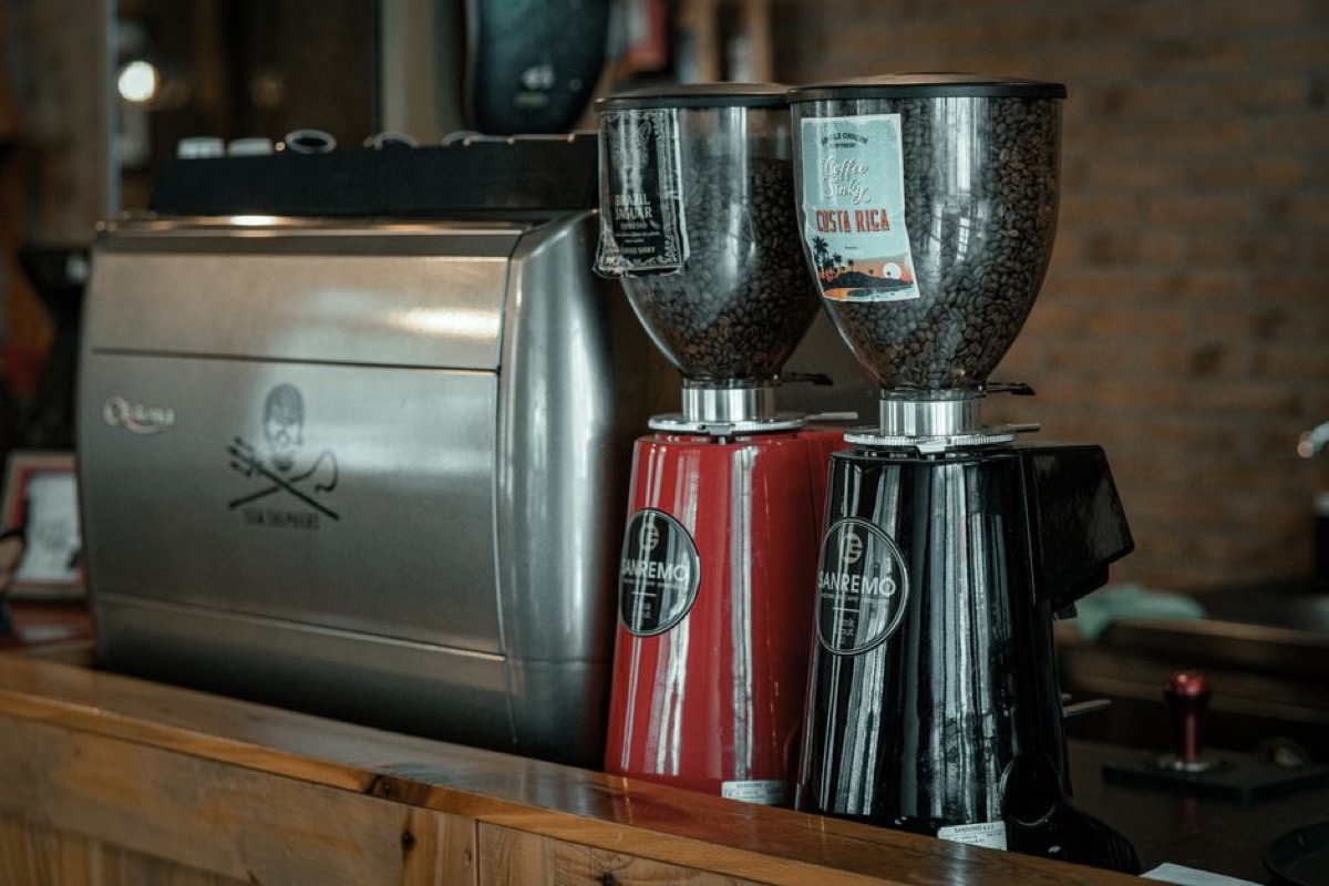 Two modern espresso grinders side by side on cafe counter with bean hoppers