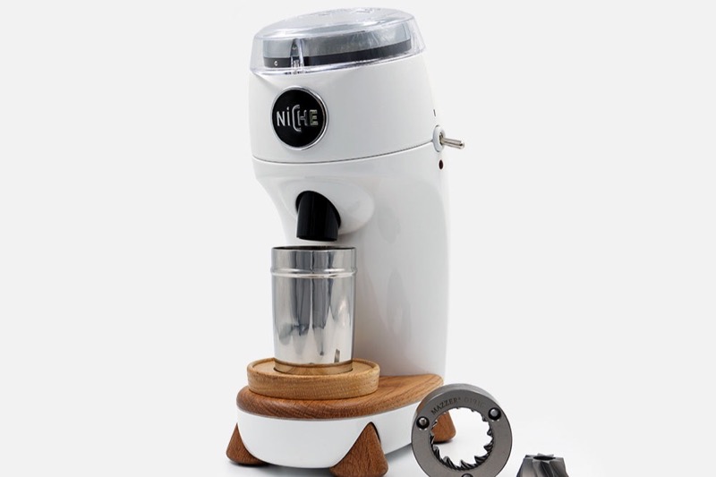 Niche Zero conical burr single-dose espresso grinder with dosing cup on a wooden base