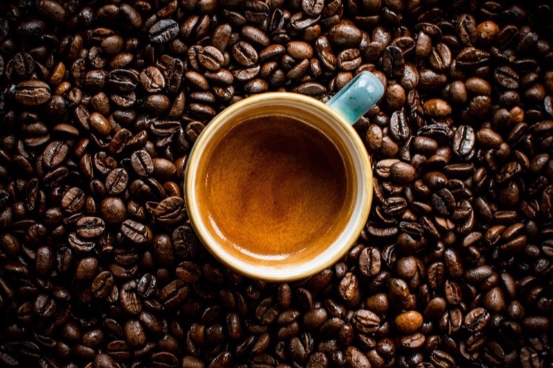 Perfectly extracted espresso shot with golden crema surrounded by dark roasted beans