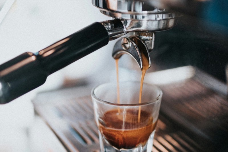 Espresso shot being pulled from a commercial espresso machine into a glass