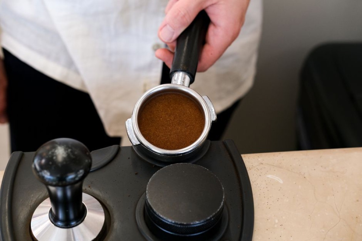 Espresso portafilter with evenly distributed grounds and tamper on a dosing station