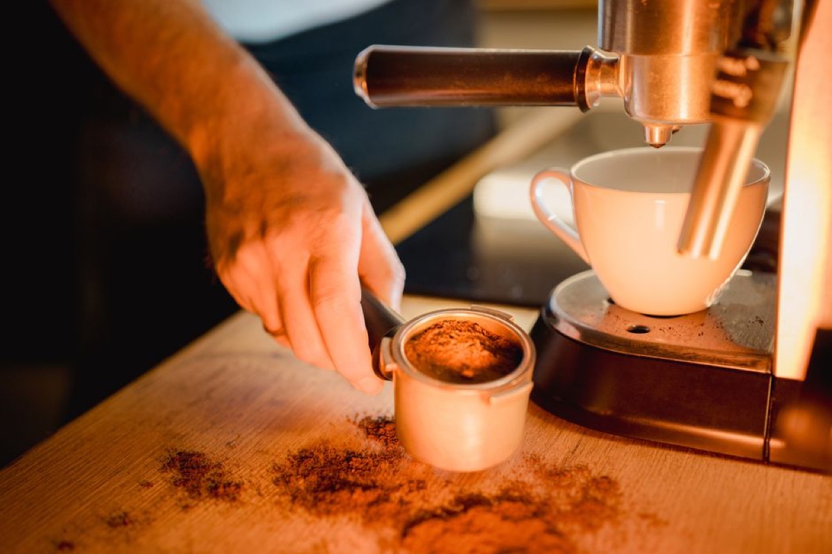 Hands holding a portafilter with freshly ground espresso coffee