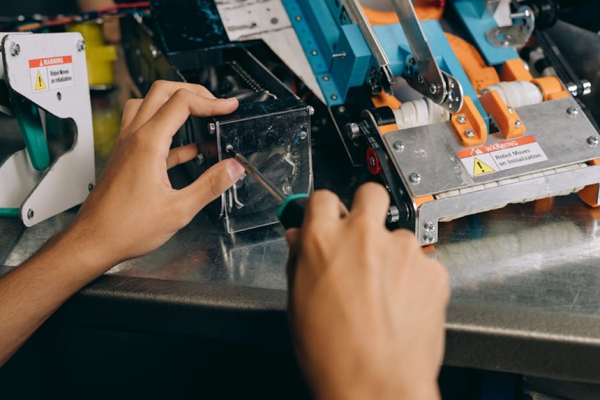 Hands working on mechanical assembly with tools on workbench