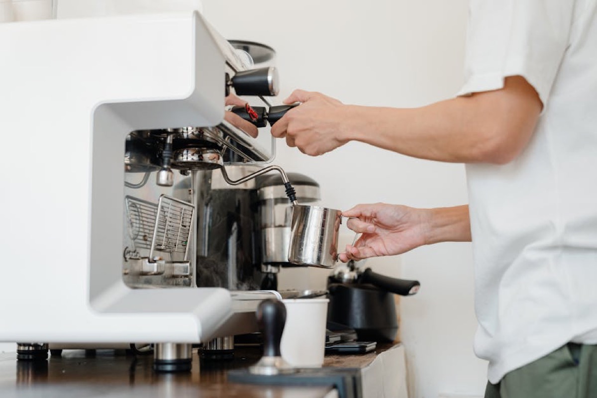 Person steaming milk at home espresso machine showing daily workflow